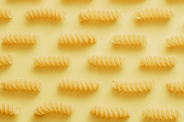 Raw fusilli pasta over yellow background.jpg