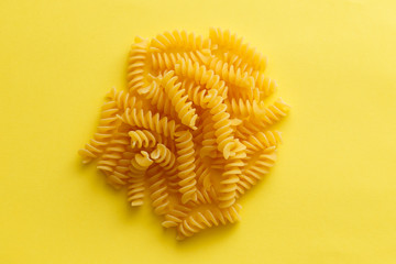 Raw fusilli pasta over yellow background.jpg