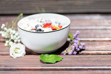 Bowl of healthy fresh fruit salad with cheese on the wooden background.
