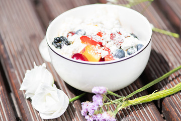 Bowl of healthy fresh fruit salad with cheese on the wooden background.