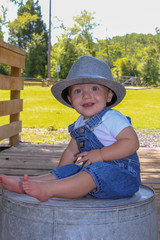 Little boy in hat and overalls on a bridge