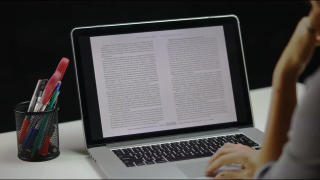 Person is thoughtfully reading text on thin notebook screen. Point of view / first person view of person scrolling and looking at laptop screen. POV.