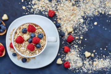 Raspberries and blueberries on blue background. Cereals.