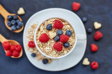 Raspberries and blueberries on blue background. Cereals.