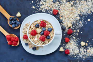 Raspberries and blueberries on blue background. Cereals.