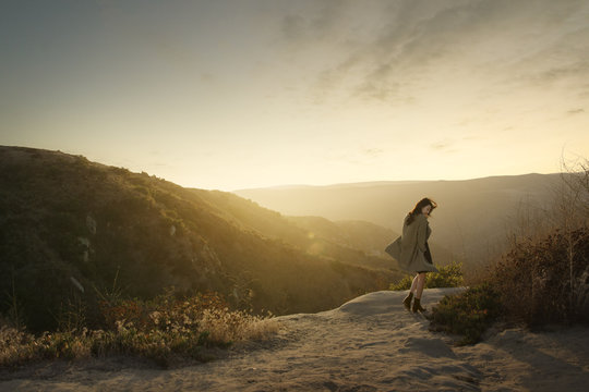 Young woman wearing boots and trench coat in mountains