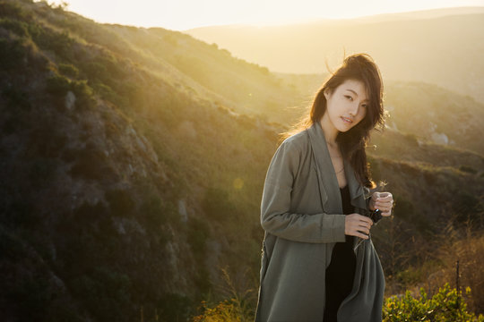Young woman standing in hazy sunlight in mountains