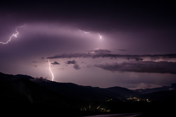 a dangerous storm in a summer night full of lighting bolts with view above the austrian city of leoben to the east