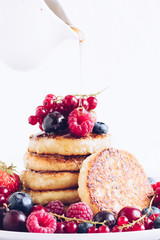 Woman pouring maple syrup on tasty pancakes