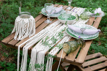 Boho style wedding reception dinning table with macrame tablecloth, decoration on a rustic wooden table © milenie
