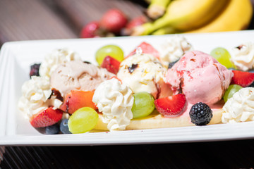 Plate of healthy fresh fruit salad with ice cream on the wooden background.