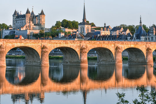 Views of the city of Saumur from the riverbank at dusk, with the castle in the background. Loire Valley, France.