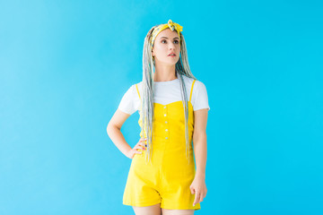 girl with dreadlocks and hand on hip posing isolated on turquoise