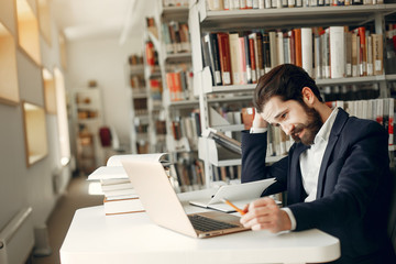 Man in a library. Guy in a black suit. Student with a books.