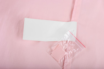 Composition clothes label with tissue samples on pink knitted background, close up