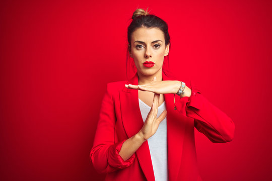 Young beautiful business woman standing over red isolated background Doing time out gesture with hands, frustrated and serious face