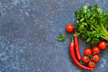 Tomatoes, chilli and parsley on a concrete, kitchen table. View from above.