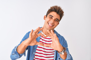 Young handsome man wearing striped t-shirt and denim shirt over isolated white background smiling in love showing heart symbol and shape with hands. Romantic concept.