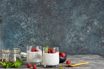 Fototapeta na wymiar Chia pudding with yogurt and raspberries in a glass on concrete background