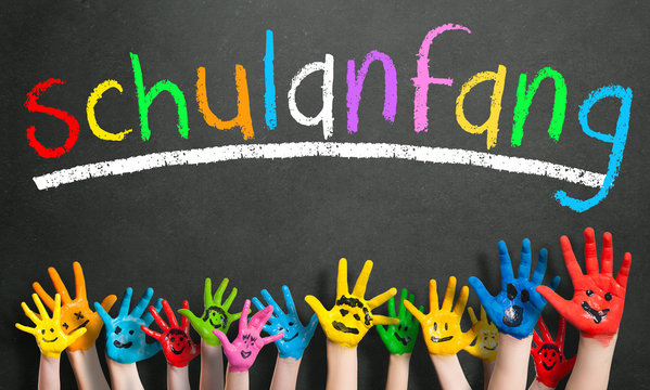 viele angemalte Kinderh&auml;nde mit Smileys vor Kreidetafel mit dem Wort "Schulanfang"