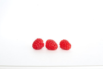 three raspberries on white background