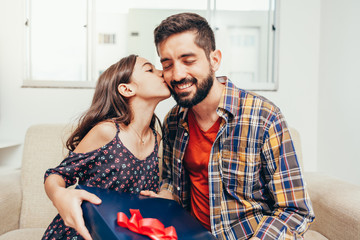 Happy father's day! Daughter congratulating dad and giving him a gift. Daddy and daughter smiling and hugging. Family holiday and togetherness