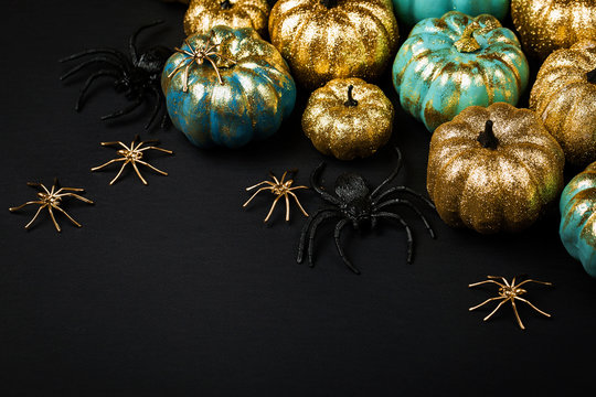 Shiny gold and blue Pumpkins with spiders. Halloween decorations. Trendy holiday concept.