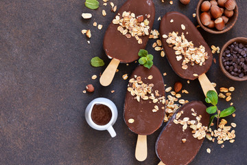 Chocolate popsicle with granola and nuts. Ice cream on a concrete background. Top view.