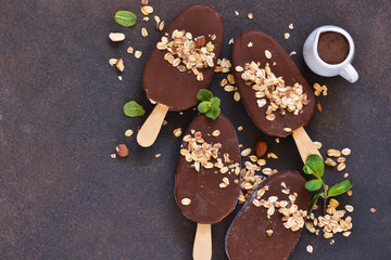 Chocolate popsicle with granola and nuts. Ice cream on a concrete background. Top view.