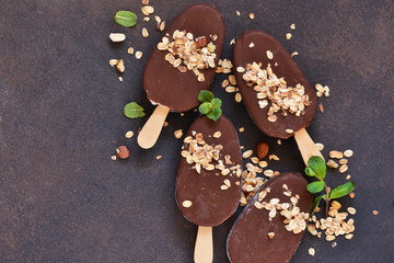 Chocolate popsicle with granola and nuts. Ice cream on a concrete background. Top view.