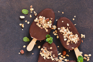 Chocolate popsicle with granola and nuts. Ice cream on a concrete background. Top view.