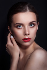 Fototapeta na wymiar Portrait of beautiful young woman with perfect young skin and red lips on dark background