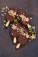 Chocolate popsicle with granola and nuts. Ice cream on a concrete background. Top view.