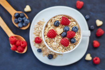Raspberries and blueberries on blue background. Cereals.