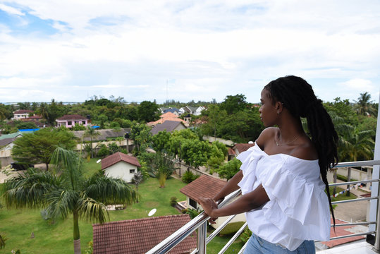 Woman looks out over buildings in tropical landscape