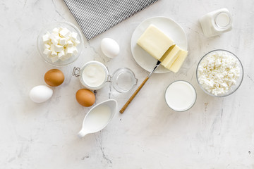 Dairy products from farm with milk, eggs, cottage, butter, yougurt on white marble background top view