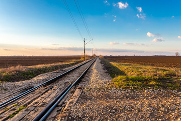 Fototapeta na wymiar Railway line between the agricultural fields in March