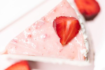 Close up of fresh strawberry tart slice on the pink plate with layered cream. Top view.