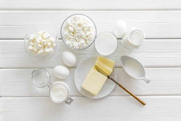 Fresh dairy products for breakfast with milk, cottage, eggs, butter, yougurt on white wooden background top view