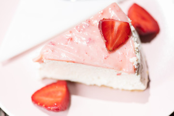 Slice of fresh strawberry tart on the pink plate with layered cream. Top view.