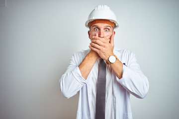 Young handsome engineer man wearing safety helmet over isolated background shocked covering mouth with hands for mistake. Secret concept.