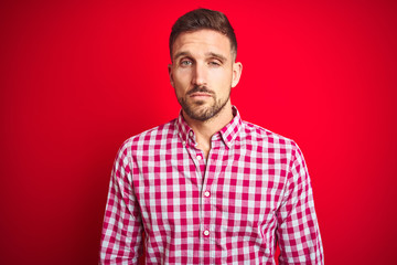 Fototapeta premium Young handsome man over red isolated background looking sleepy and tired, exhausted for fatigue and hangover, lazy eyes in the morning.