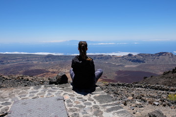 Woman looking at a dry and rocky volcanic landscape on Teide - Spain