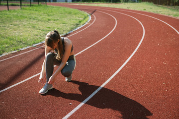 Sportswoman on racetrack tying shoes
