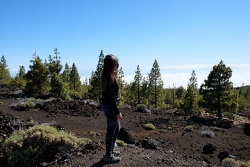 Woman ascending the Teide mountain peak on a dry and rocky volcanic landscape