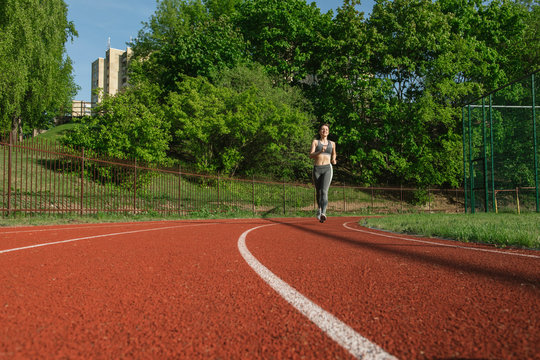 Sportswoman running on racetrack