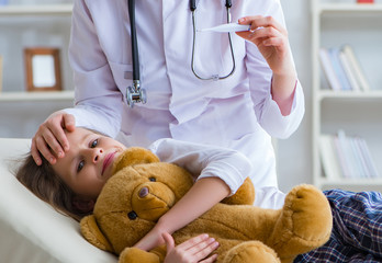 Woman female doctor examining little cute girl with toy bear