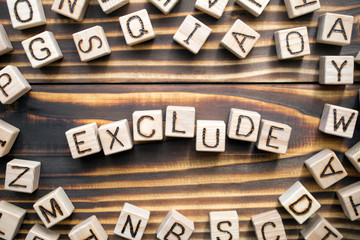 exclude wooden cubes with letters, to keep out or omit concept, around the cubes random letters, top view on wooden background