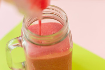 making raspberry smoothie (colorful background). selective focus.