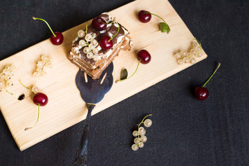 Top view of a slide of chocolate cake with a cherry on a black background